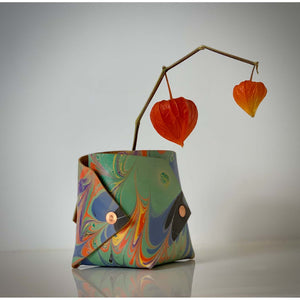 Load image into Gallery viewer, Marbled leather Origami inspired vessel.  Abstract pattern in orange, green and purple.  Finished with copper rivets.  Contains orange dried flowers