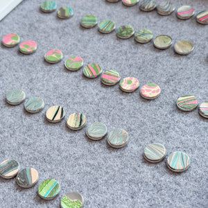 Load image into Gallery viewer, Marbled leather stainless steel studs on grey felt backing.