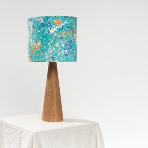 Load image into Gallery viewer, Lamp, unlit, sitting on natural linen tablecloth with white background.  Linen lampshade in Stone marbling pattern in dark teal and dark peach on a cone shaped wooden base
