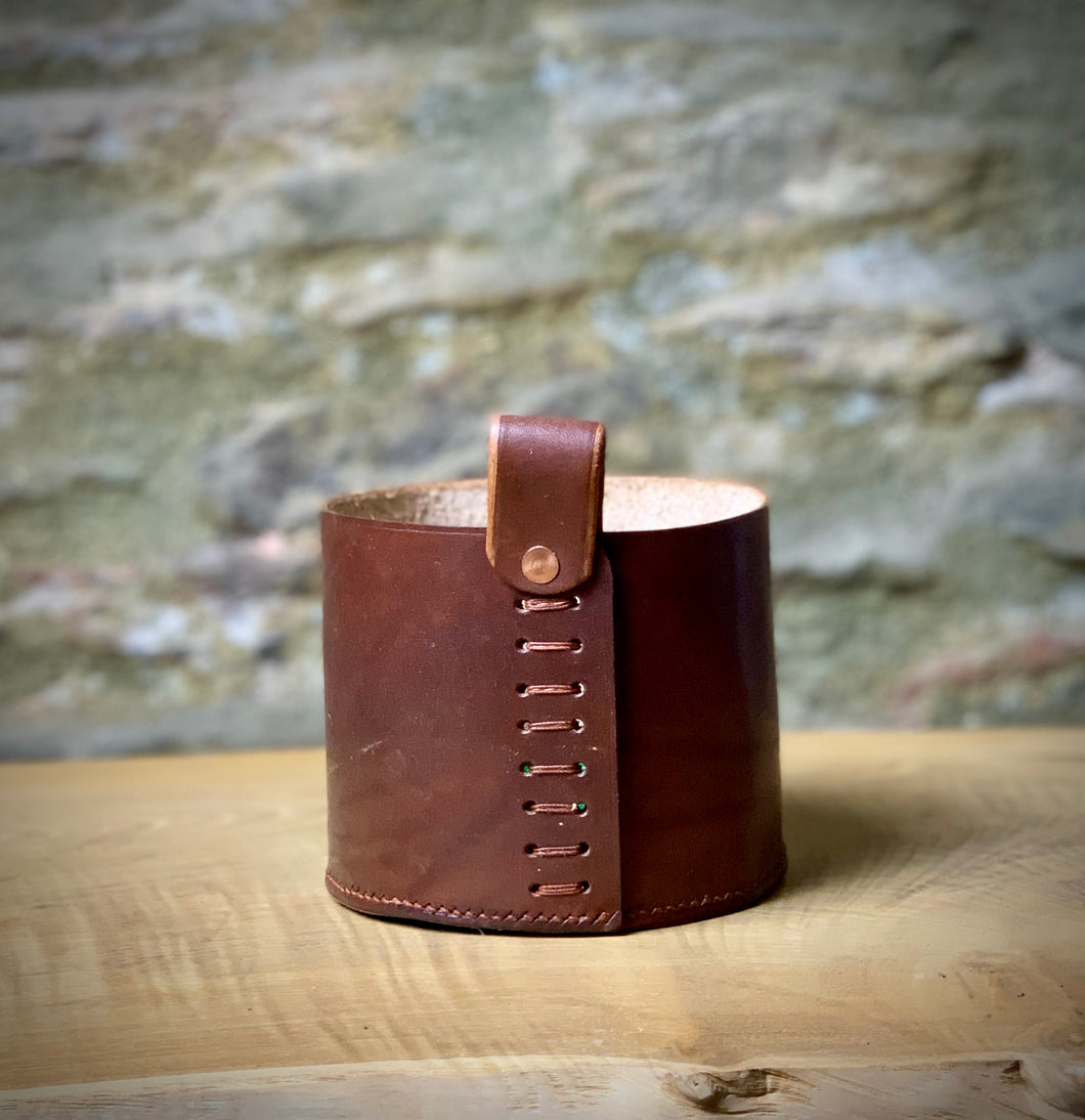 Leather storage pot, in small.  Use as a plant pot, or for pen pot in the home office.  Oak bark veg-tanned leather in Dark London Tan.  Hand-stitched base using traditional saddle stitch for strength and loop attached with a ladder stitch and copper rivet.